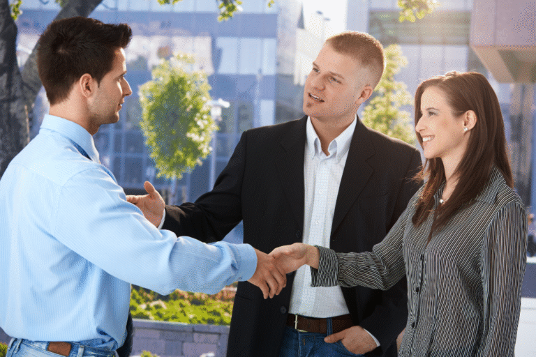 Businesspeople shaking hands outdoors, representing trust-based referrals in broker relationships, a key factor in any broker sourcing comparison.