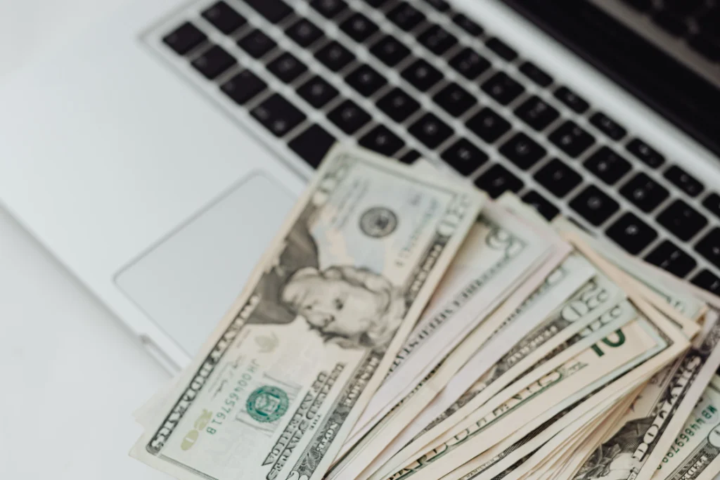 A stack of $10 and $20 bills resting on a laptop keyboard and trackpad, representing the financial terms and compensation outlined by a termination clause engagement letter.