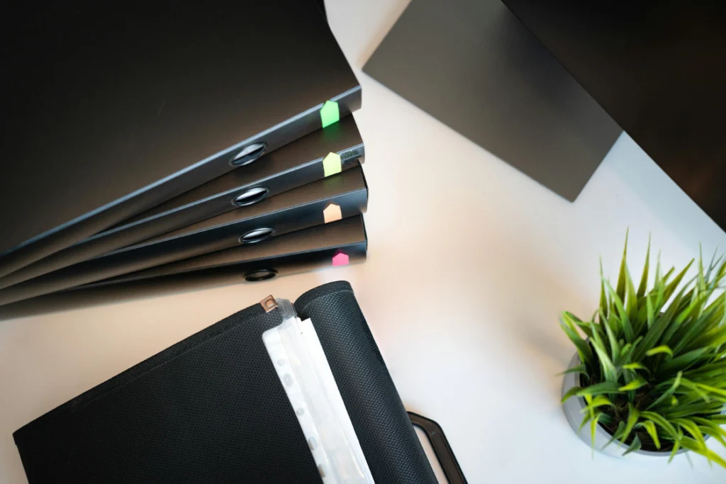 Stack of black binders with colorful index tabs, symbolizing organized documentation for a scope of work engagement letter.
