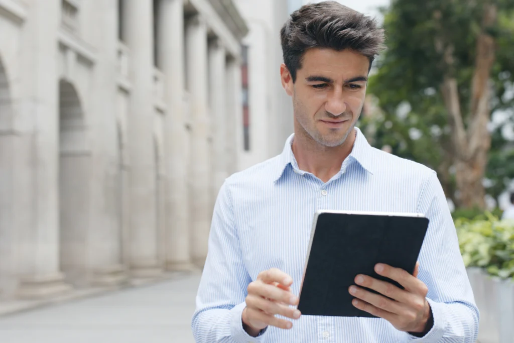 Man outdoors reviewing a digital copy of a scope of work engagement letter on a tablet.