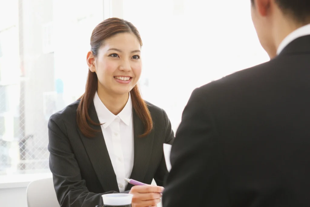 Woman in a business interview smiling confidently, representing trustworthy SMB broker traits such as honesty and professionalism.