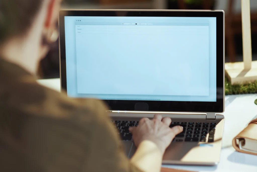 A person's hand typing an email on a laptop, signifying the requirement for giving written notice for termination as specified in an engagement letter.