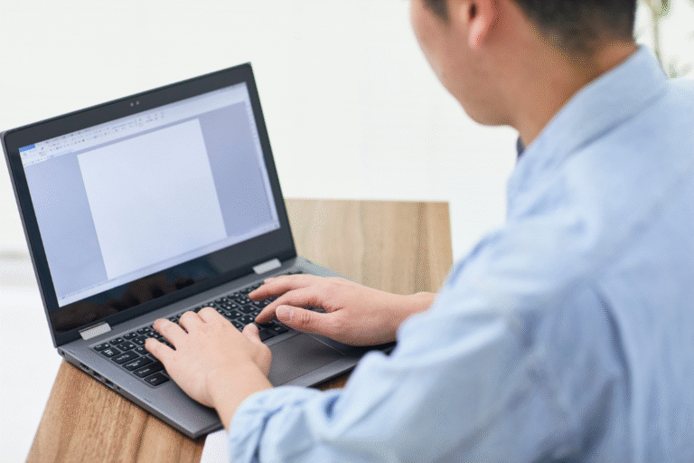 Person typing on a laptop to write an engagement letter for selling a business.