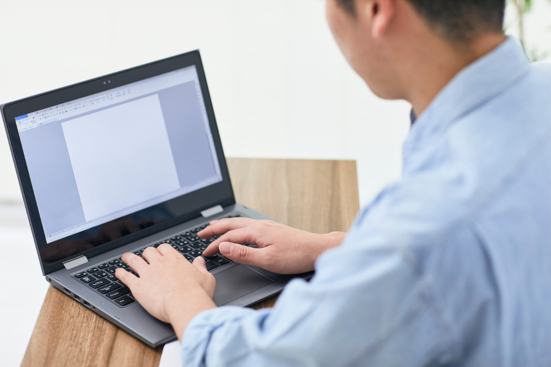 Person typing on a laptop to write an engagement letter for selling a business.