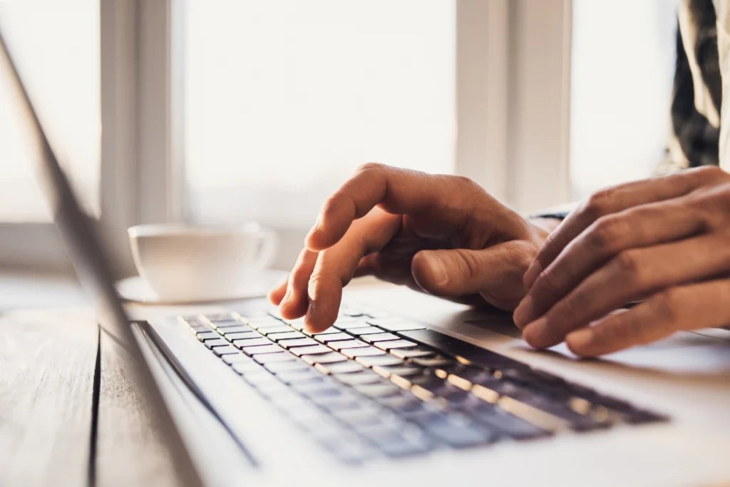 Close-up of hands typing on a laptop keyboard, representing the act of writing the scope of work engagement letter clause.