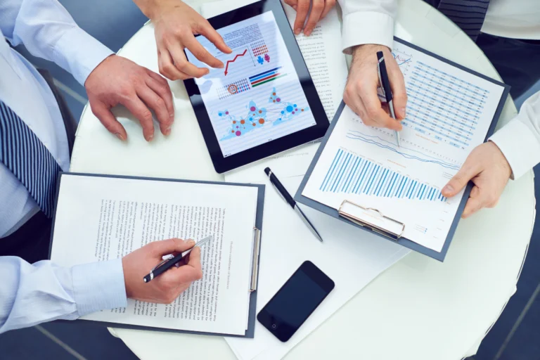 Overhead view of a team planning with papers, charts, and a laptop on offers received business sale strategy