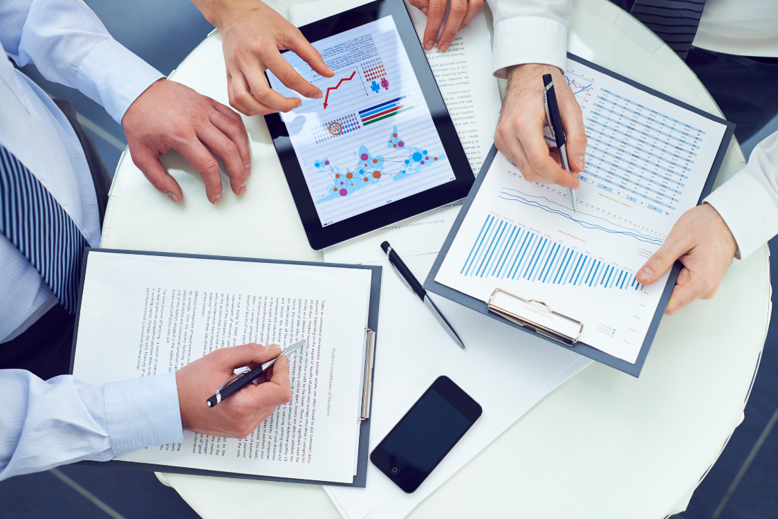 Overhead view of a team planning with papers, charts, and a laptop on offers received business sale strategy