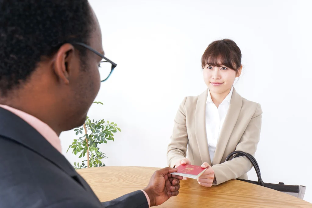 A professional handing a passport/document to another, representing the exchange of verified lead information during the lead qualification process.