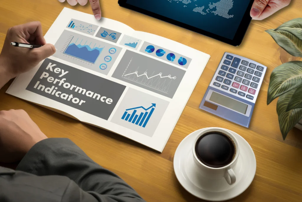 Close-up of hands pointing at a document titled "Key Performance Indicator" next to a calculator, emphasizing the measurement of financial KPIs for selling a business.