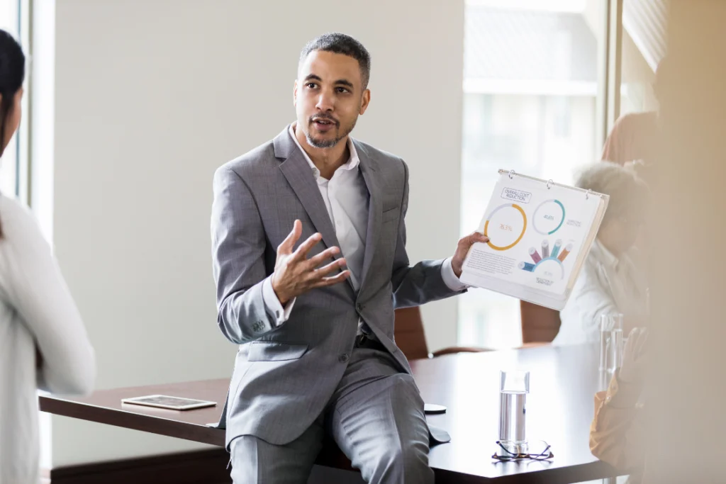 Businessman in a suit presenting a circular chart on a clipboard, discussing offers received business sale data