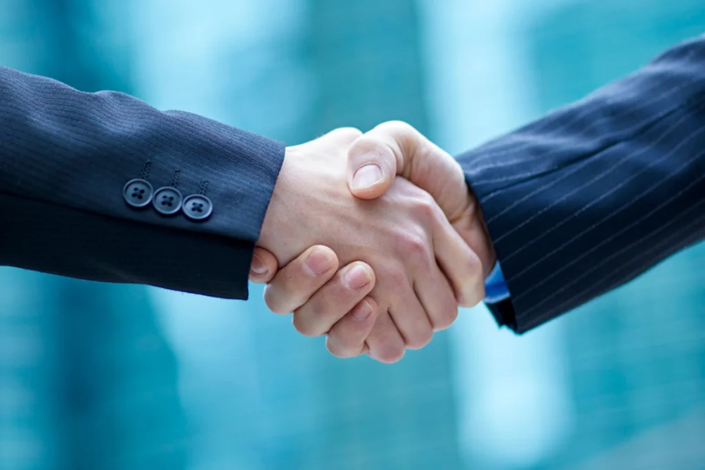 A close-up handshake between two professionals in dark suits, symbolizing the closing of a deal with a serious, qualified lead.