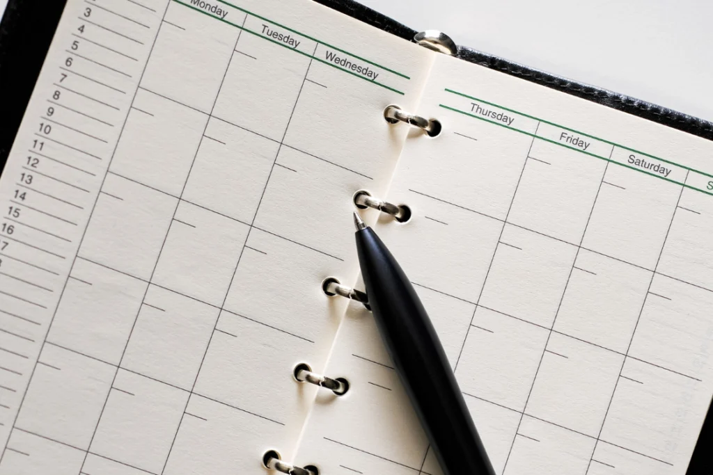 - A planner and pen used by sales leaders to schedule activities as part of weekly KPI tracking for business sale, aiming to increase leads and shorten the sales cycle.