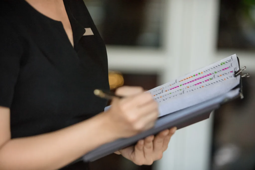 Sales managers using a pen to update a tracking sheet, essential for monitoring kpis to track like customer retention and improving sales performance.