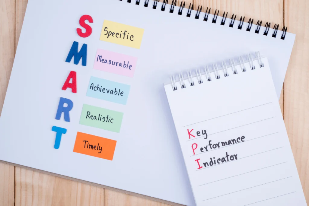 A notepad showing the SMART framework (Specific, Measurable, Achievable, Realistic, Timely), which is essential for defining effective KPIs for selling a business.