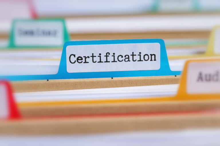 Close-up of a blue folder tab clearly labeled "Certification" in a set of business files, representing the importance of a business valuation certification.