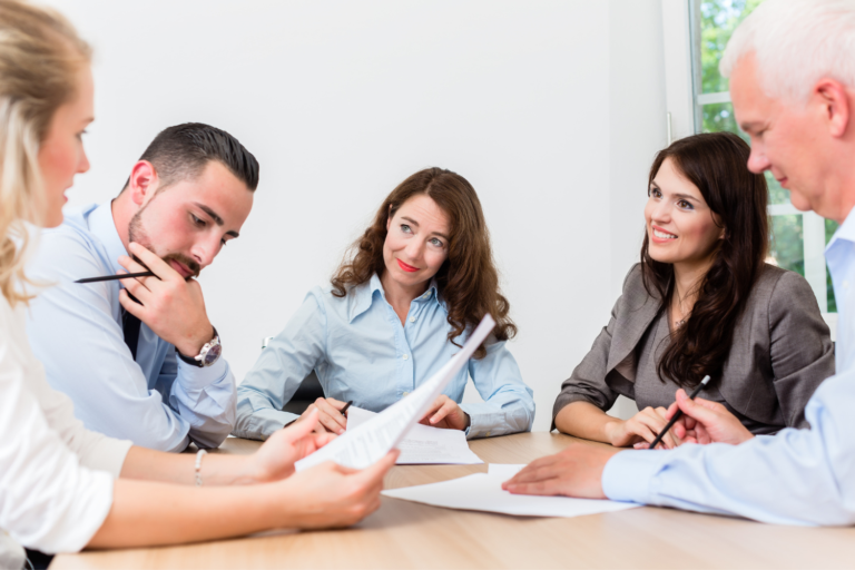 A group sits around a table, reviewing documents.