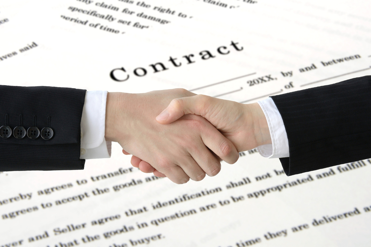 Business handshake with contract document visible