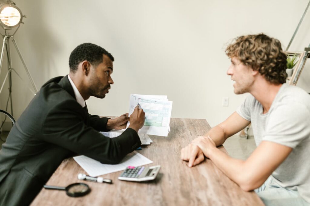 Financial advisor discussing paperwork with a client across a desk in a modern office