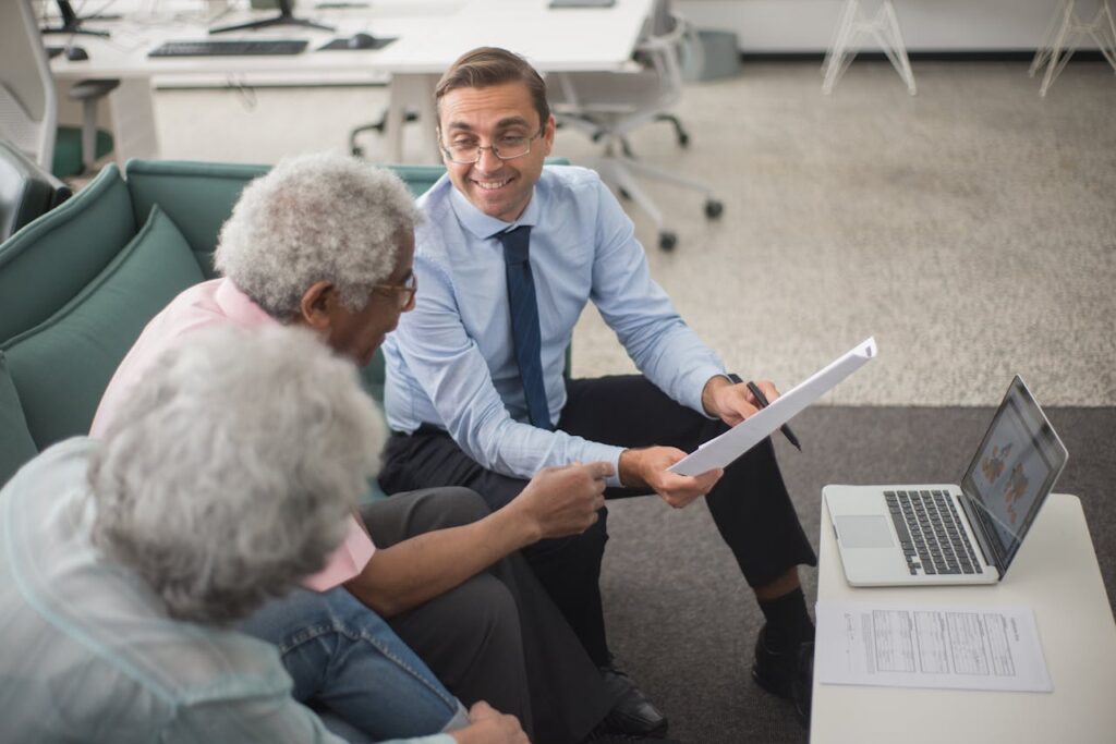 Consultant discussing financial plans with senior clients using documents and laptop