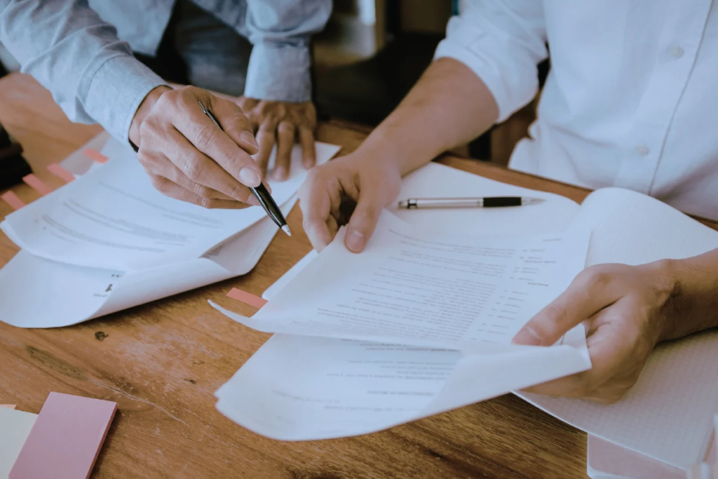 Two business professionals reviewing documents at a wooden table, illustrating the daily operational challenges of an owner dependent business.