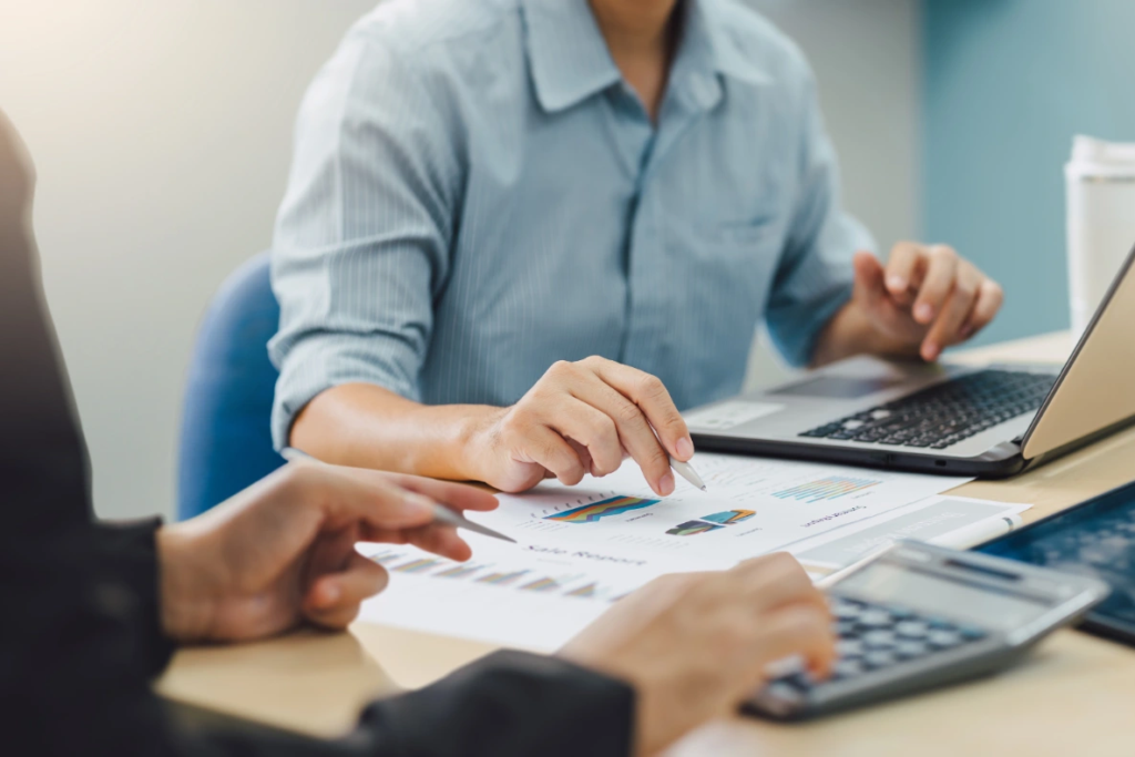 Two people reviewing financial documents at a table with a laptop and calculator, showing how an average valuation is usually done.