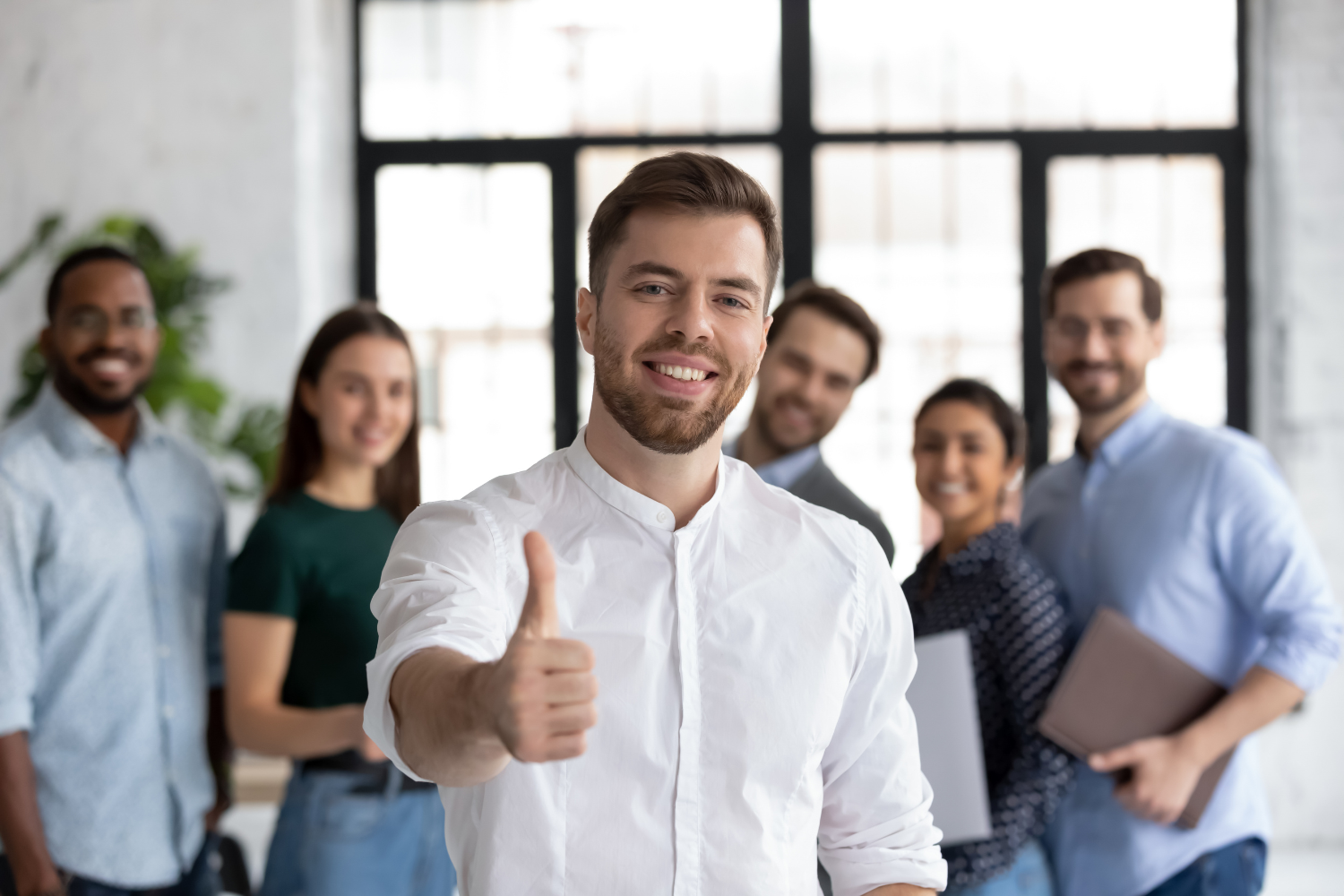 Group of professionals in an office with one person giving a thumbs-up, symbolizing customer satisfaction signal check through reviews, retention, and feedback.