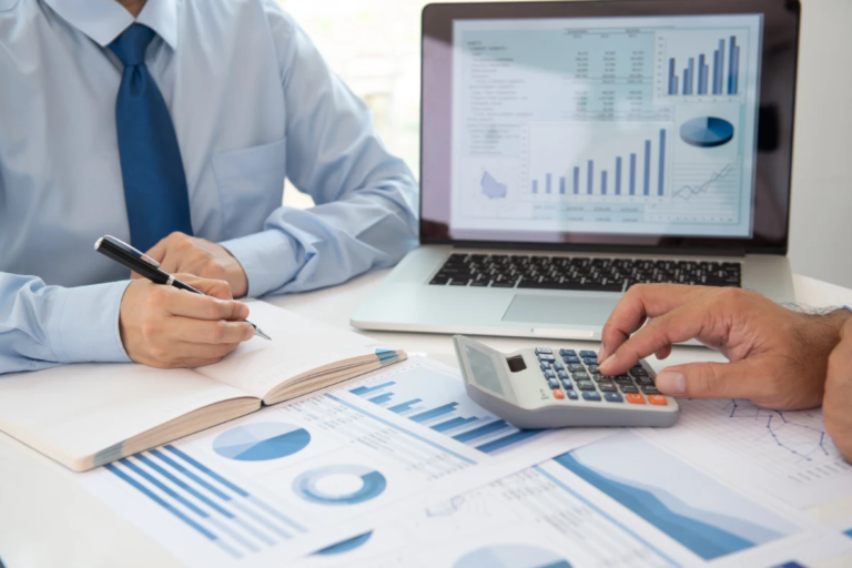 Two professionals analyzing financial charts with laptop and calculator during a business valuation review.