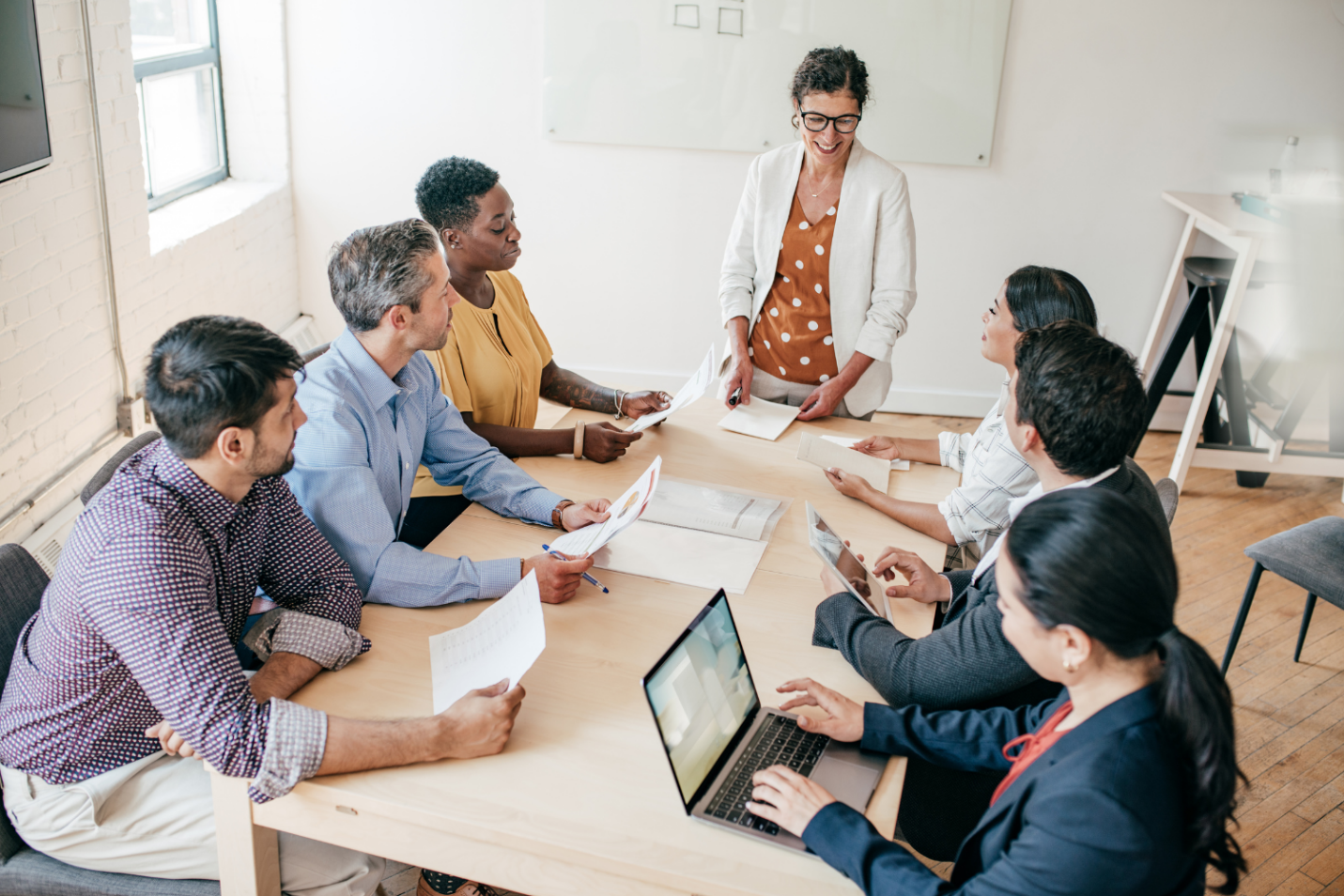 Team meeting discussing selling a business strategy, with six professionals collaborating around a conference table.