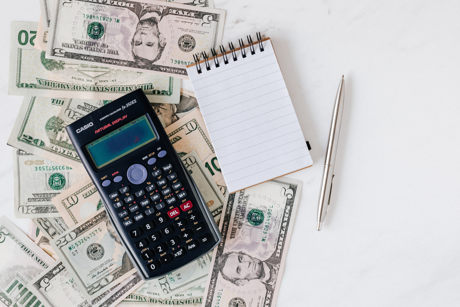 Calculator, cash, notebook, and pen showing how broker fees, debt, taxes, and closing costs can reduce net proceeds from a business sale.
