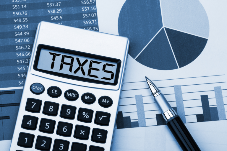Calculator showing taxes beside financial charts and a pen, representing how taxes can reduce the net proceeds from selling a business.