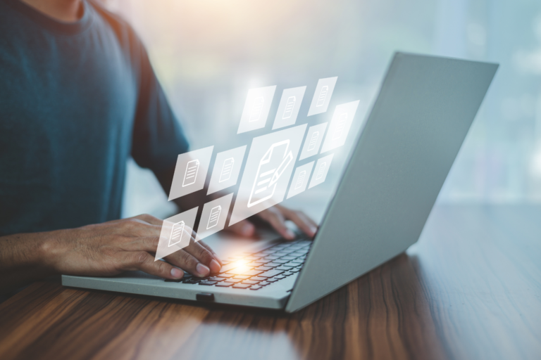 Person using a laptop with digital document icons, representing a technology due diligence checklist for business sellers.
